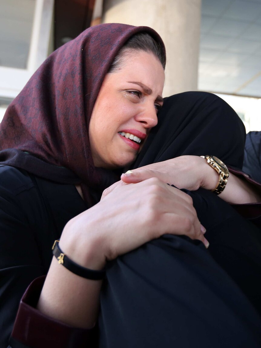 An Iranian woman cries as she hugs her mother