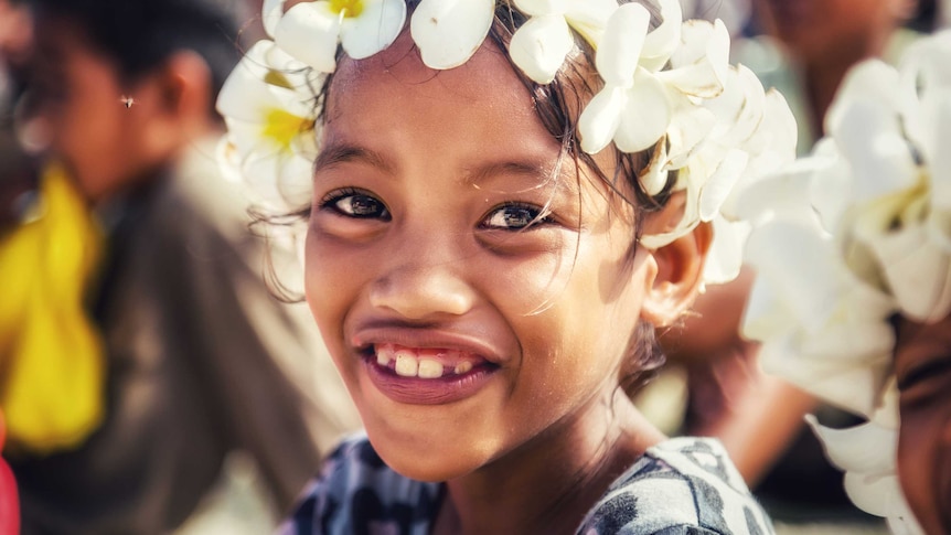 A young girl wears a frangipani wreath.