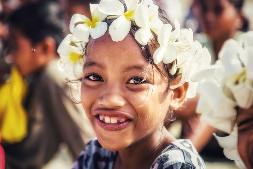 A young girl wears a frangipani wreath.