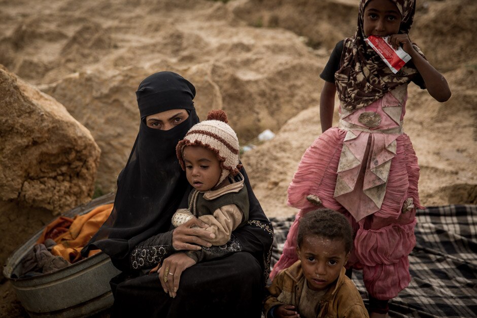 A woman and her children sit on the ground in the Khamer displacement camp in Yemen’s Amran province.