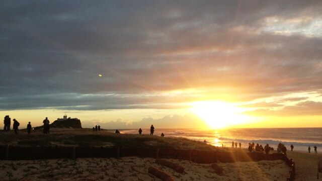 People stand on Newcastle's Nobbys Beach after the city's Anzac Day dawn service.