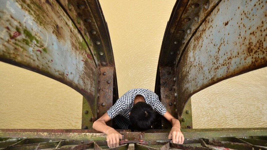 Looking down at a boy climbing down a ladder on a railway bridge