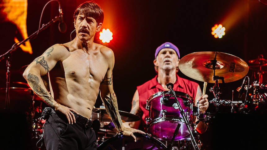 Anthony Kiedis stands on stage shirtless in front of drummer Chad Smith