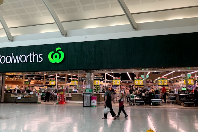 a supermarket entry way with the Woolworths logo visible above it.