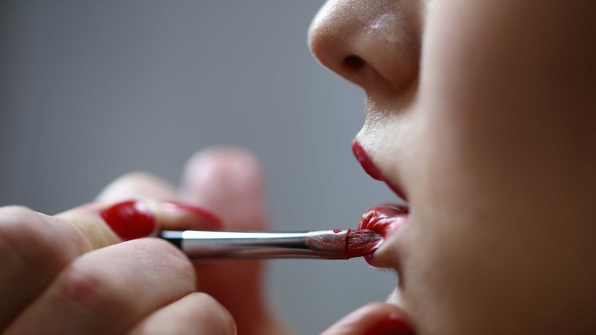 Woman applying lipstick.