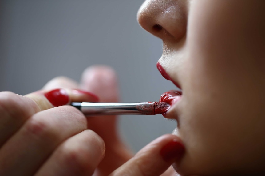 Woman applying lipstick.