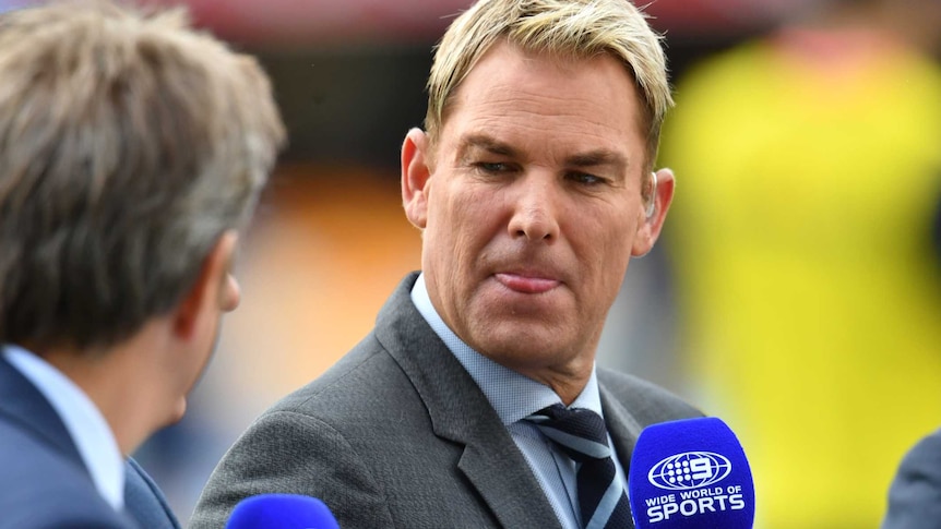 Shane Warne holding a microphone during Nine cricket coverage