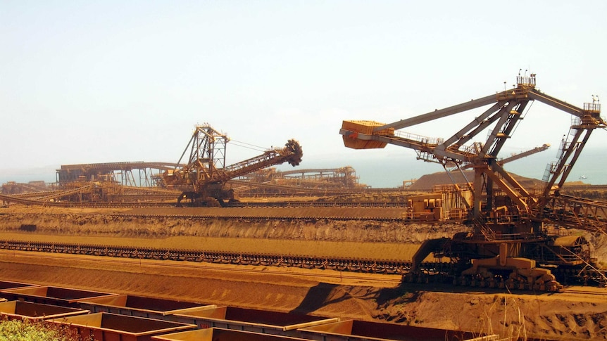 Stackers and reclaimers moving iron ore to rail cars at Rio Tinto's Port Dampier operations in WA's Pilbara region.