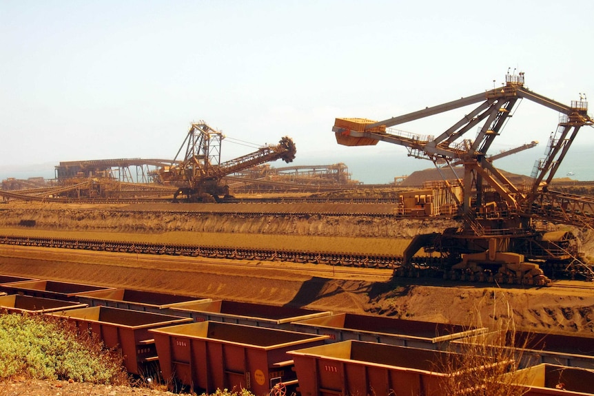 Stackers and reclaimers moving iron ore to rail cars at Rio Tinto's Port Dampier operations in WA's Pilbara region.