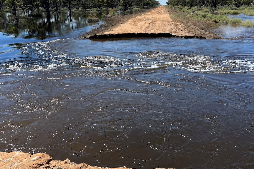 Floodwater cuts access on a country dirt road.