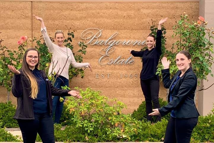 several people standing around a sign smiling