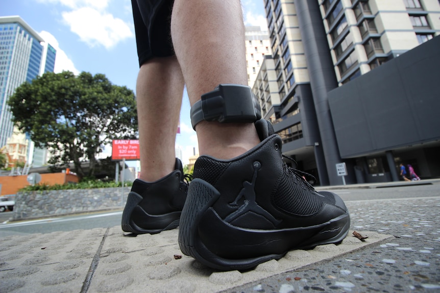 Queensland police GPS tracker on an ankle worn by a person on a Brisbane city street.