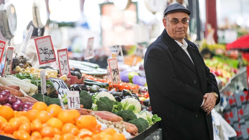 Robert Costa leans on a fruit and vegetable display in a grocery store