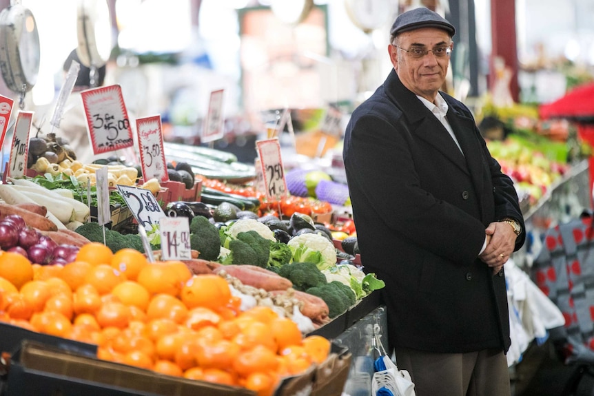 Robert Costa leans on a fruit and vegetable display in a grocery store