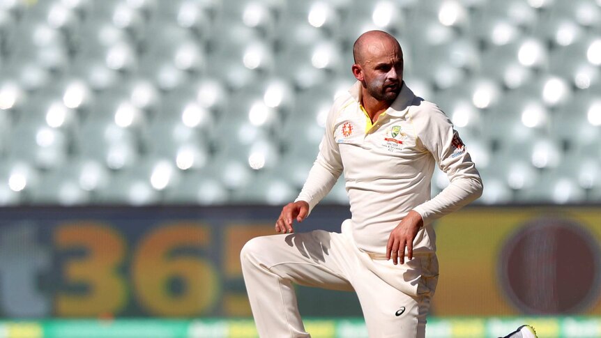 Nathan Lyon kneels down and looks over his shoulder