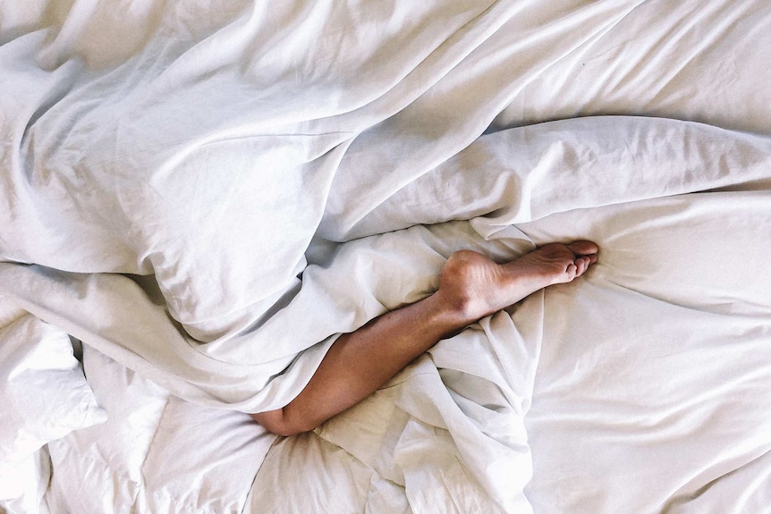 Woman's legs under a sheet in bed