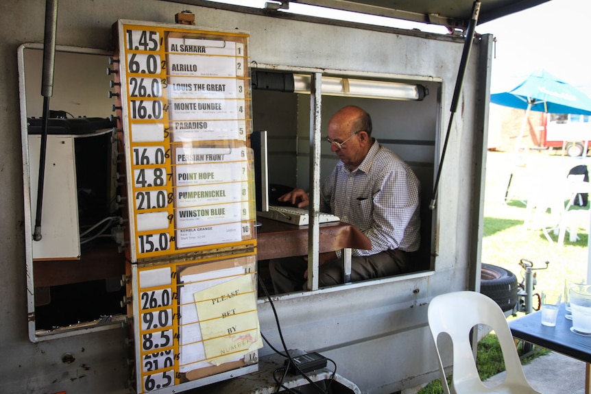 A race bookie in a small caravan calculating odds