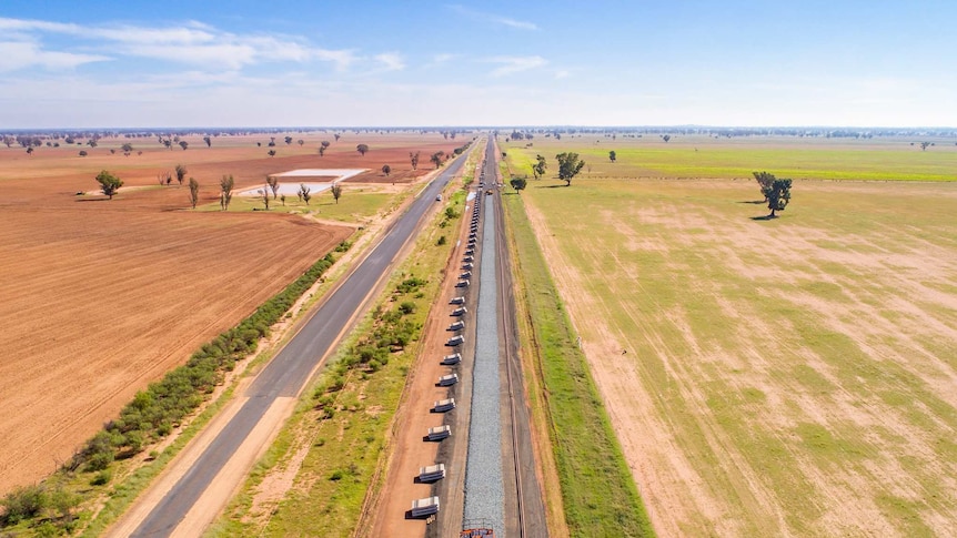 A drone image of a railway line under construction, with paddocks either side.