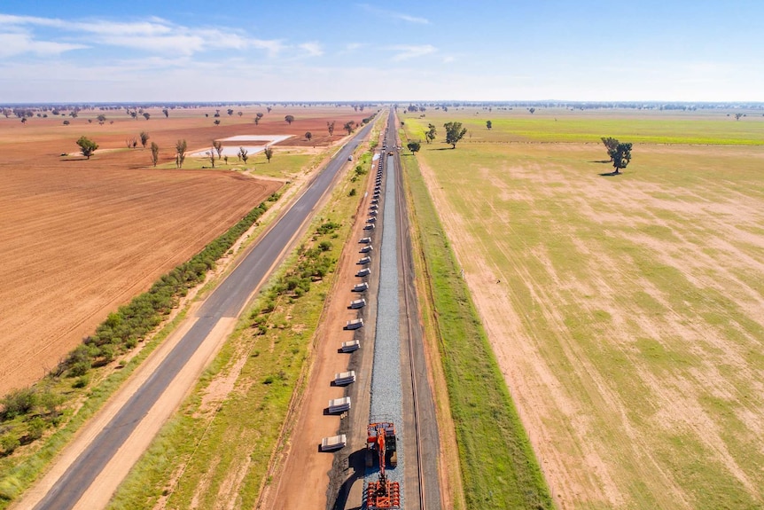 A drone image of a railway line under construction, with paddocks either side.