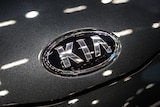 The KIA logo is seen up close on a charcoal grey car.