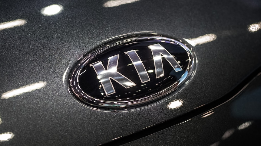 The KIA logo is seen up close on a charcoal grey car.