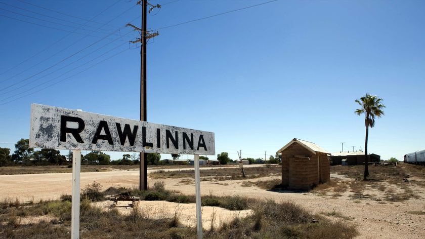Sign post reading 'Rawlinna' next to a train line in the remote Western Australian town.