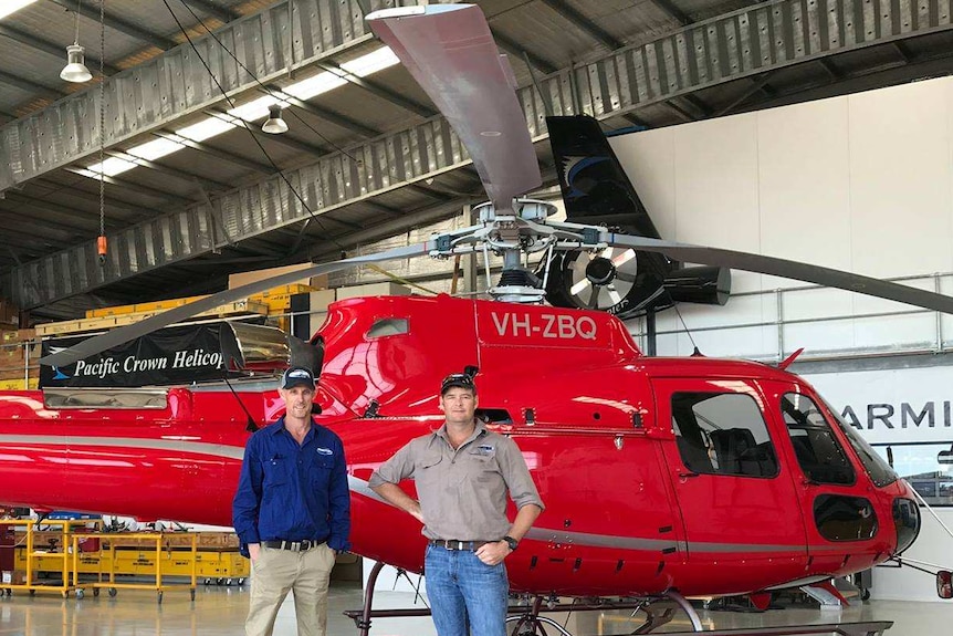 Martin Inglis and Dan Grant stand with a helicopter