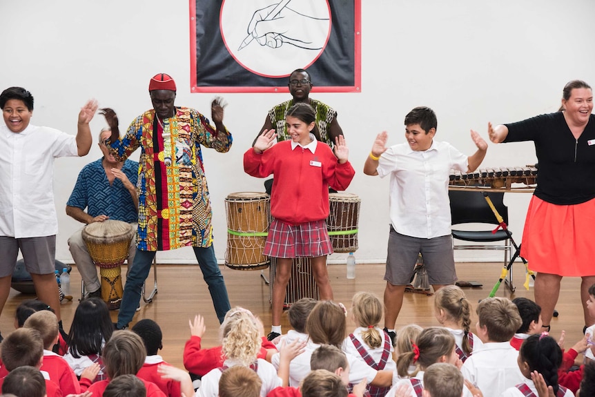 Performers and students dance in front of a school audience.