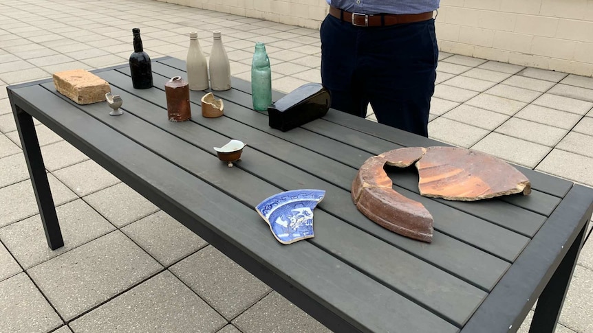 A table with cracked ceramics and glassware.