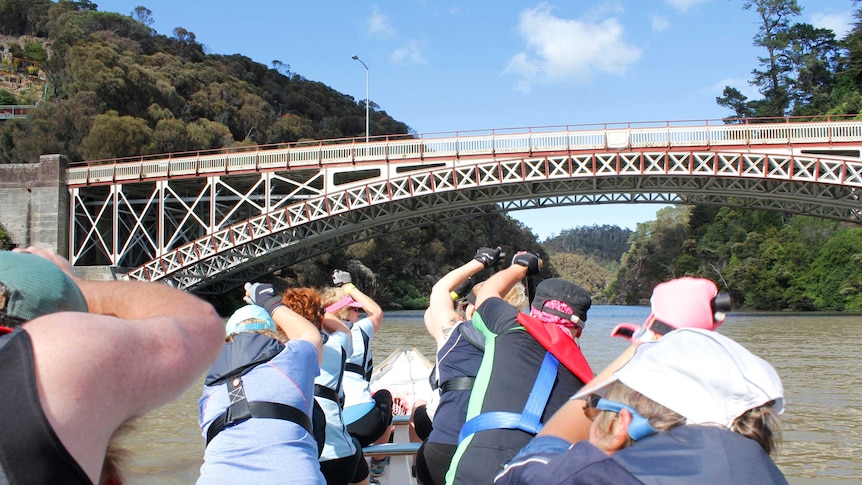 Looking at crew paddling form the back of the dragon boat with bridge up ahead