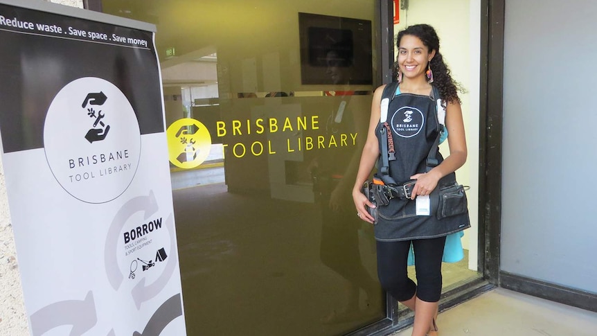 Sabrina Chakori, dressed with tool belt, stands outside entrance to the Brisbane Tool Library.
