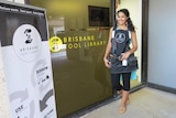 Sabrina Chakori, dressed with tool belt, stands outside entrance to the Brisbane Tool Library.