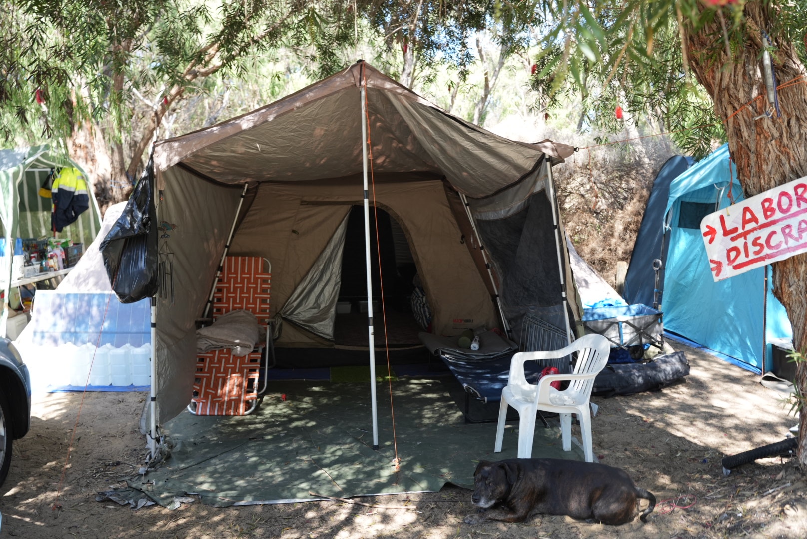 A brown tent can be seen with several chairs placed outside the flap