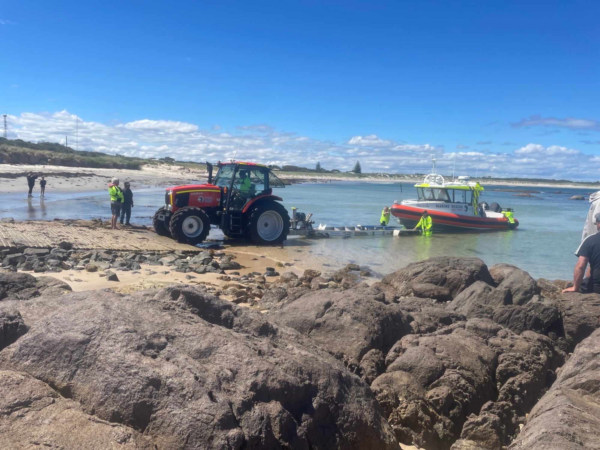 Un bote de rescate marítimo se baja al mar con grandes rocas en primer plano