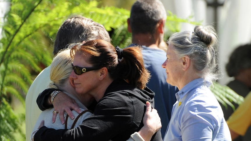 Mourners embrace during a memorial service at Kinglake