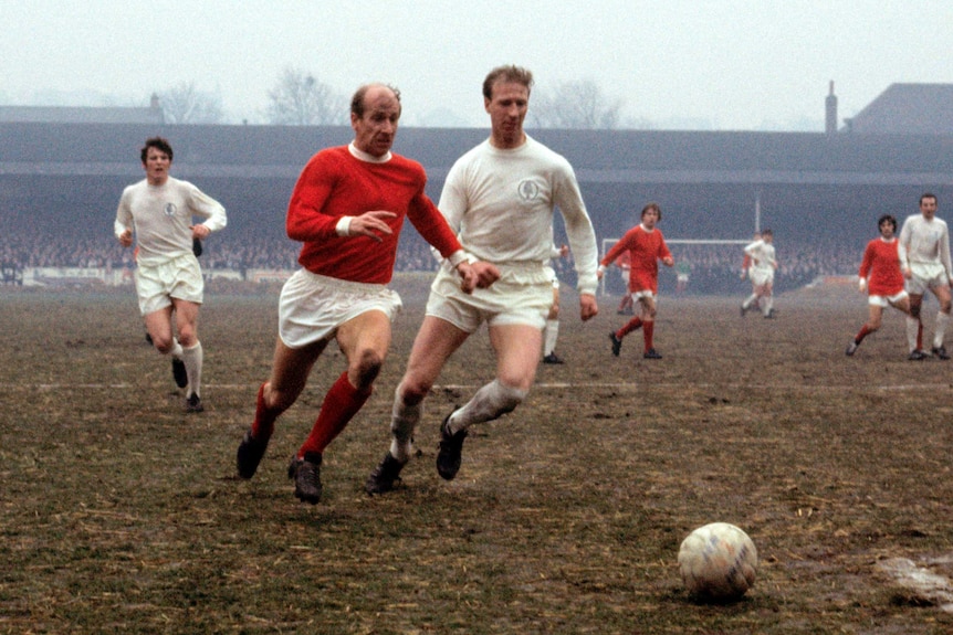 An old photo of Bobby Charlton, in his Manchester United kit, and Jack Charlton, in his Leeds kit, running after the ball