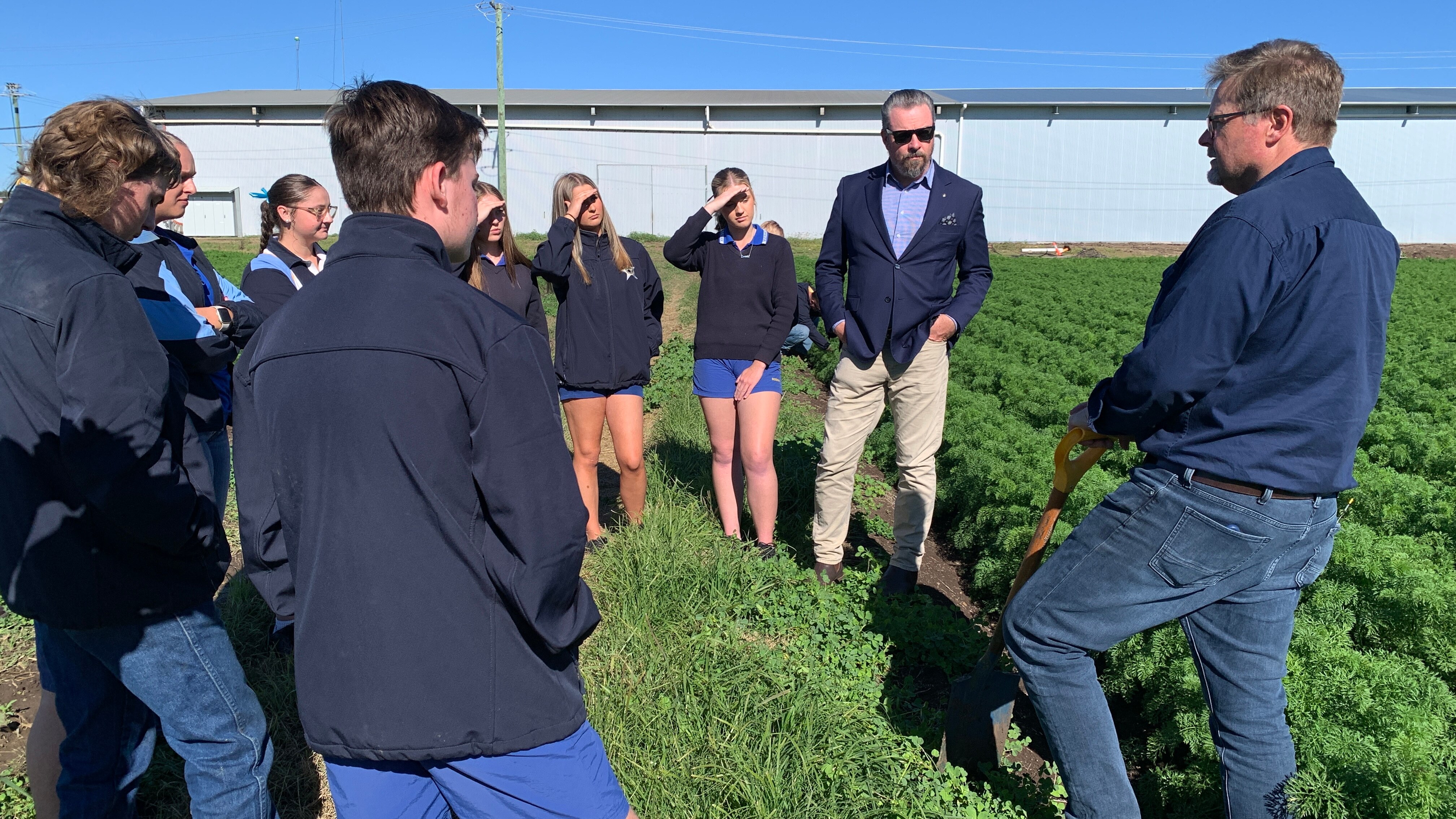 Los estudiantes se encuentran en un prado verde en Kalfresh, donde el propietario explica cómo funciona la empresa.