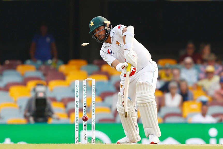 The ball smacks into the off stump, dislodging a bail, as Yasir Shah plays an awkward and unsuccessful shot.