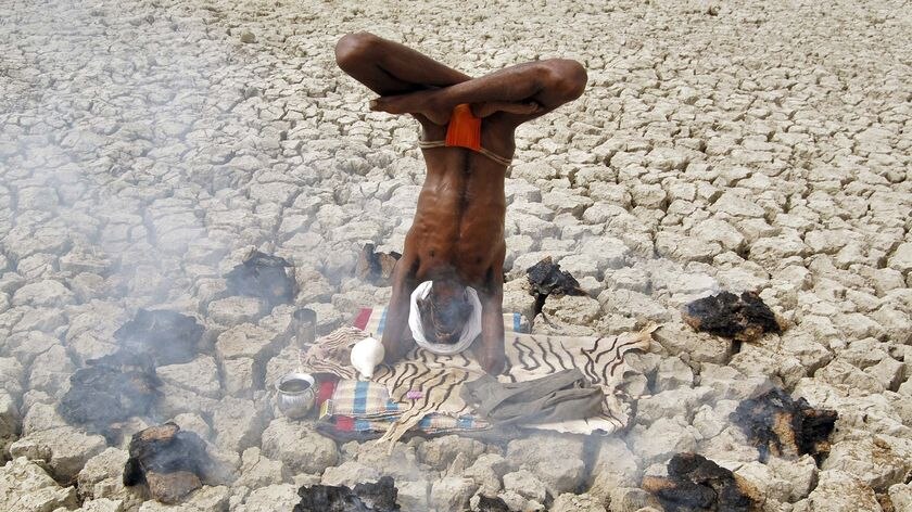 A Hindu holyman performs yoga in a dry pond