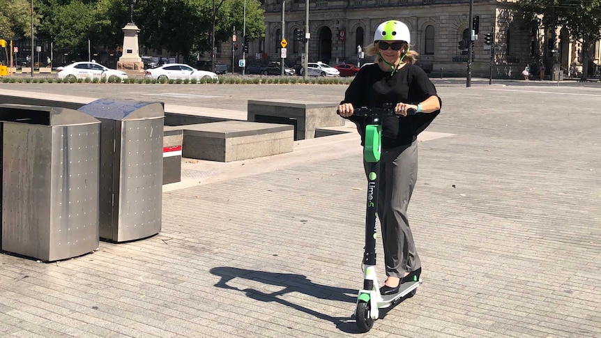 A woman rides an electric scooter in Adelaide.