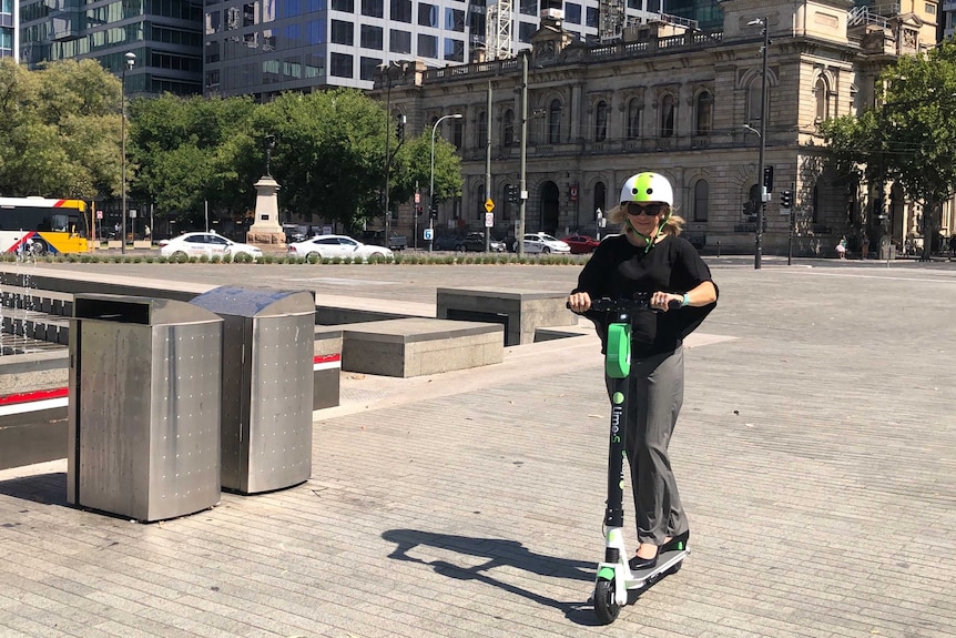 A woman rides an electric scooter in Adelaide.