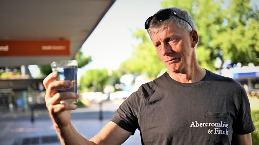 A man gazes suspiciously at a glass of water