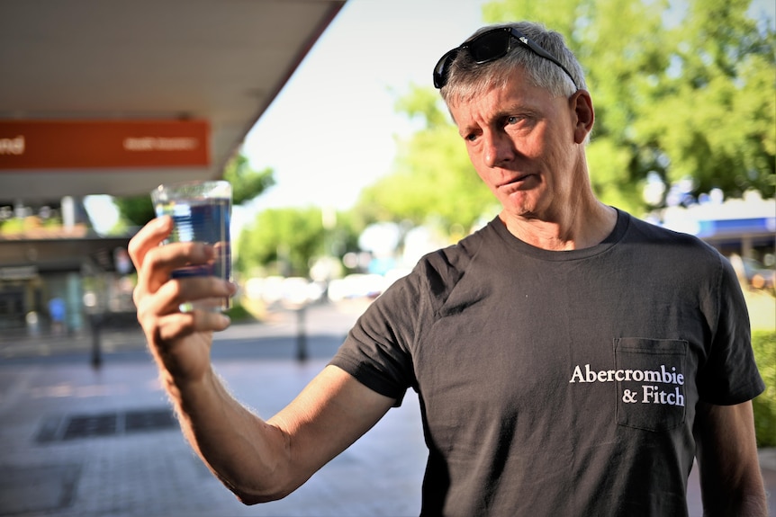 A man gazes suspiciously at a glass of water