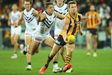 Hawthorn's Sam Mitchell handballs while being tackled by Fremantle's Stephen Hill