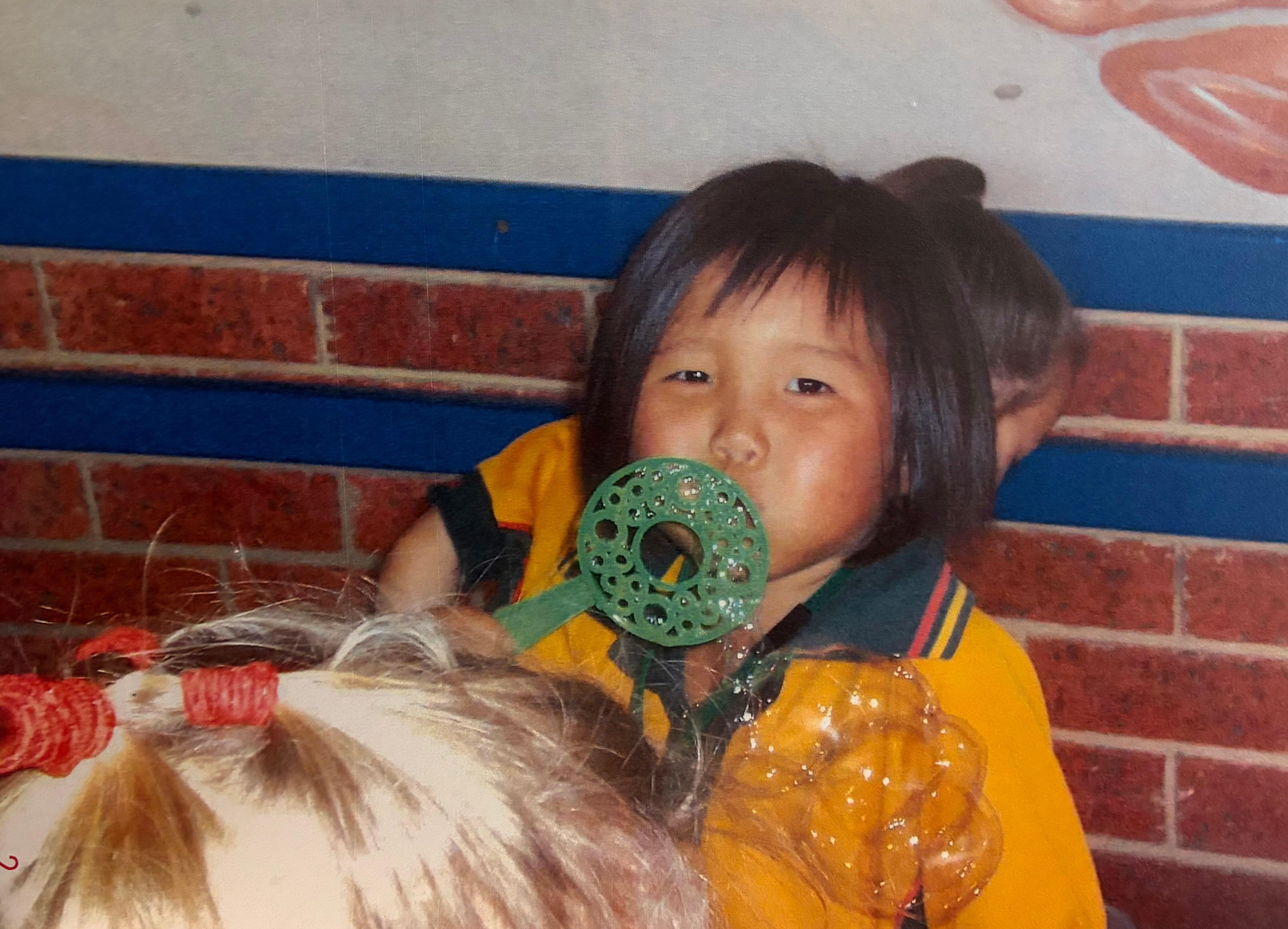 Una joven de cabello oscuro con un uniforme escolar claro juega con un soplador de burbujas en la escuela.