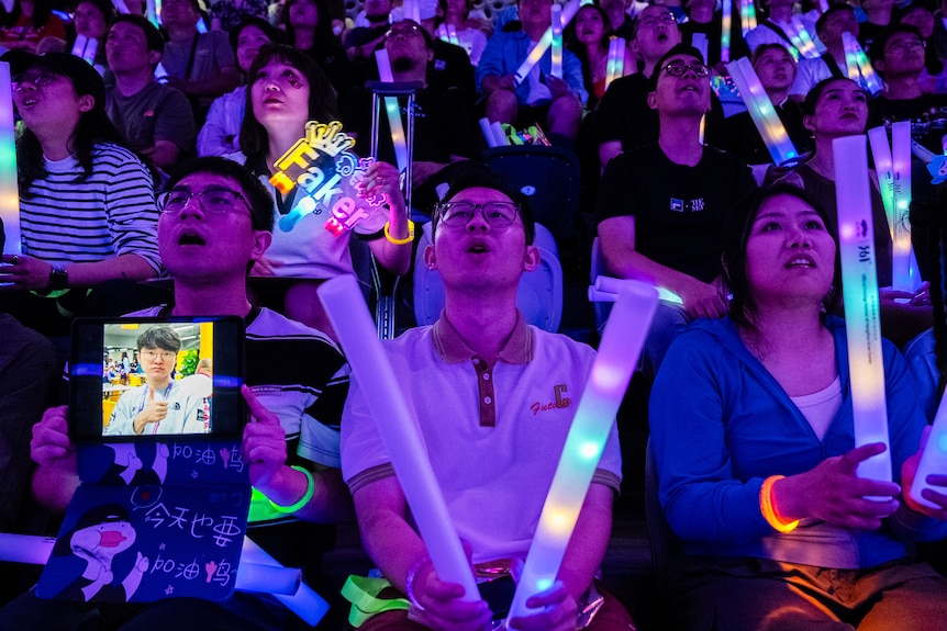 Fans holding signs for South Korean player Lee Sang-hyeok, known as 'Faker', react during the Esports League of Legends final.
