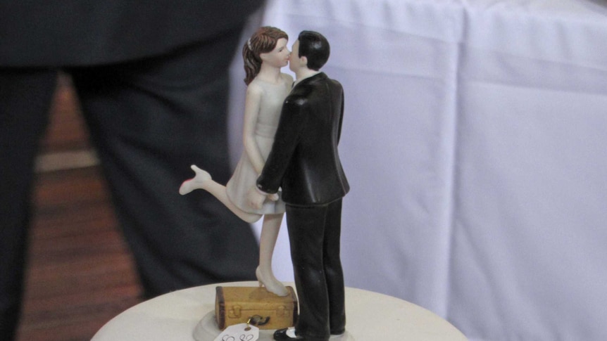 Bride and groom figurines on white wedding cake.