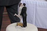 Bride and groom figurines on white wedding cake.