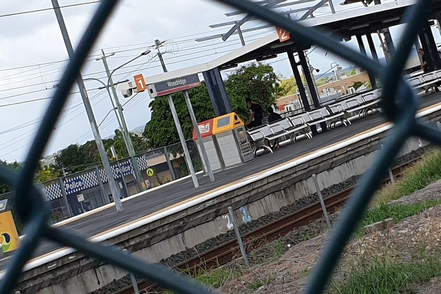 Generic photo of Woodridge train station sign and platform through fence.