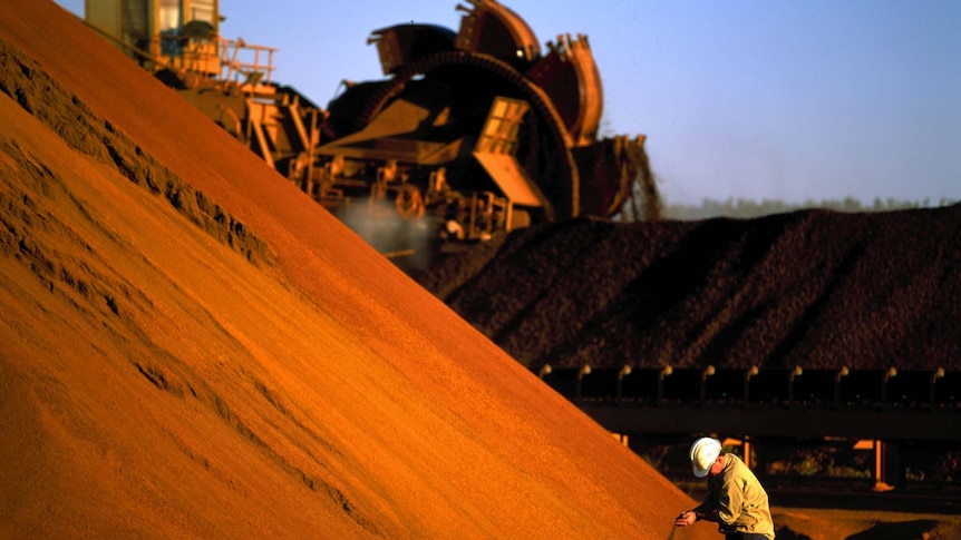 A worker inspects iron ore stockpiles in Marandoo, in Western Australia's Pilbara.